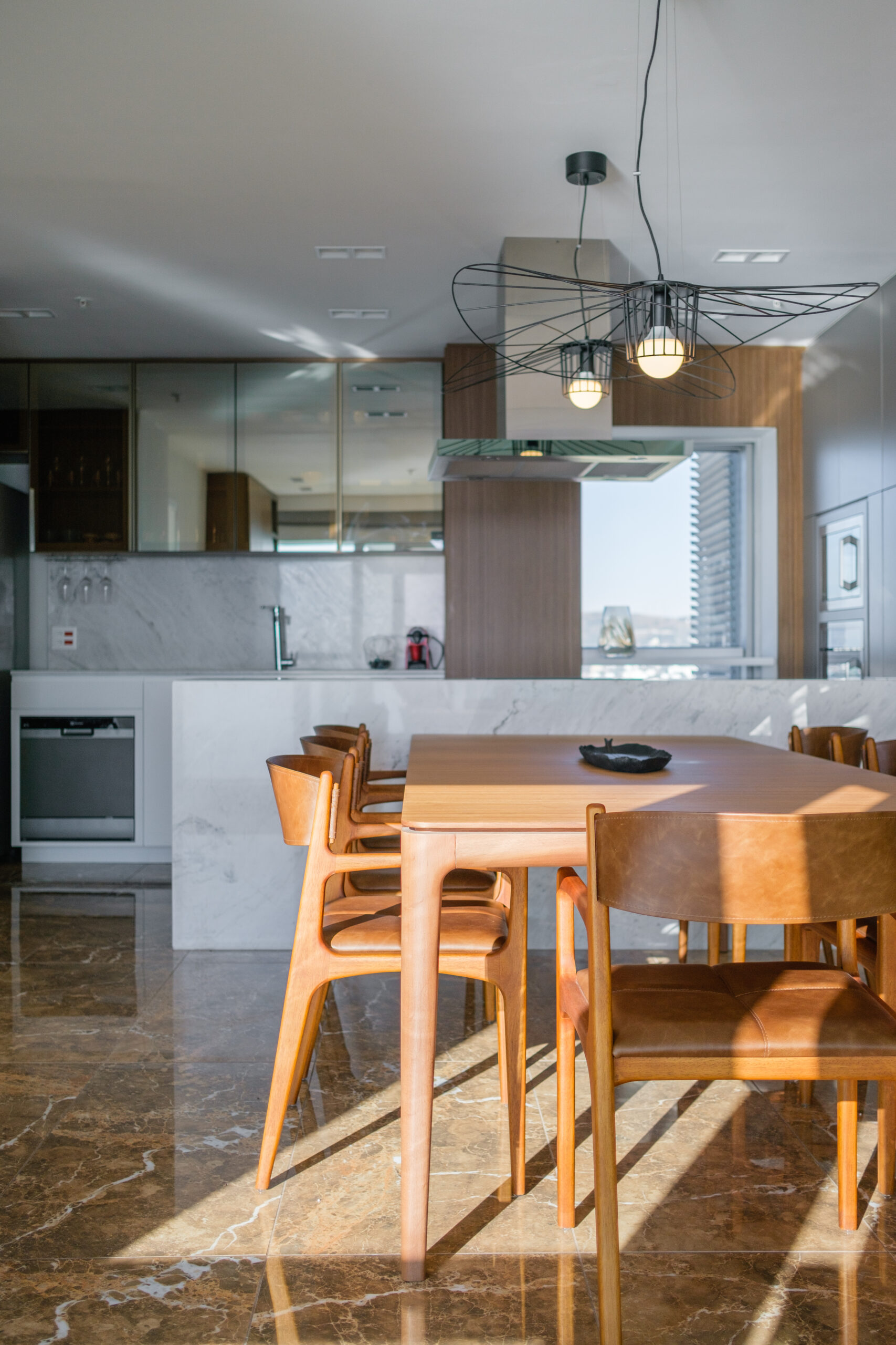 sala de jantar com cozinha integrada, mesa em madeira e cadeiras em madeira e couro. bancada em pedra